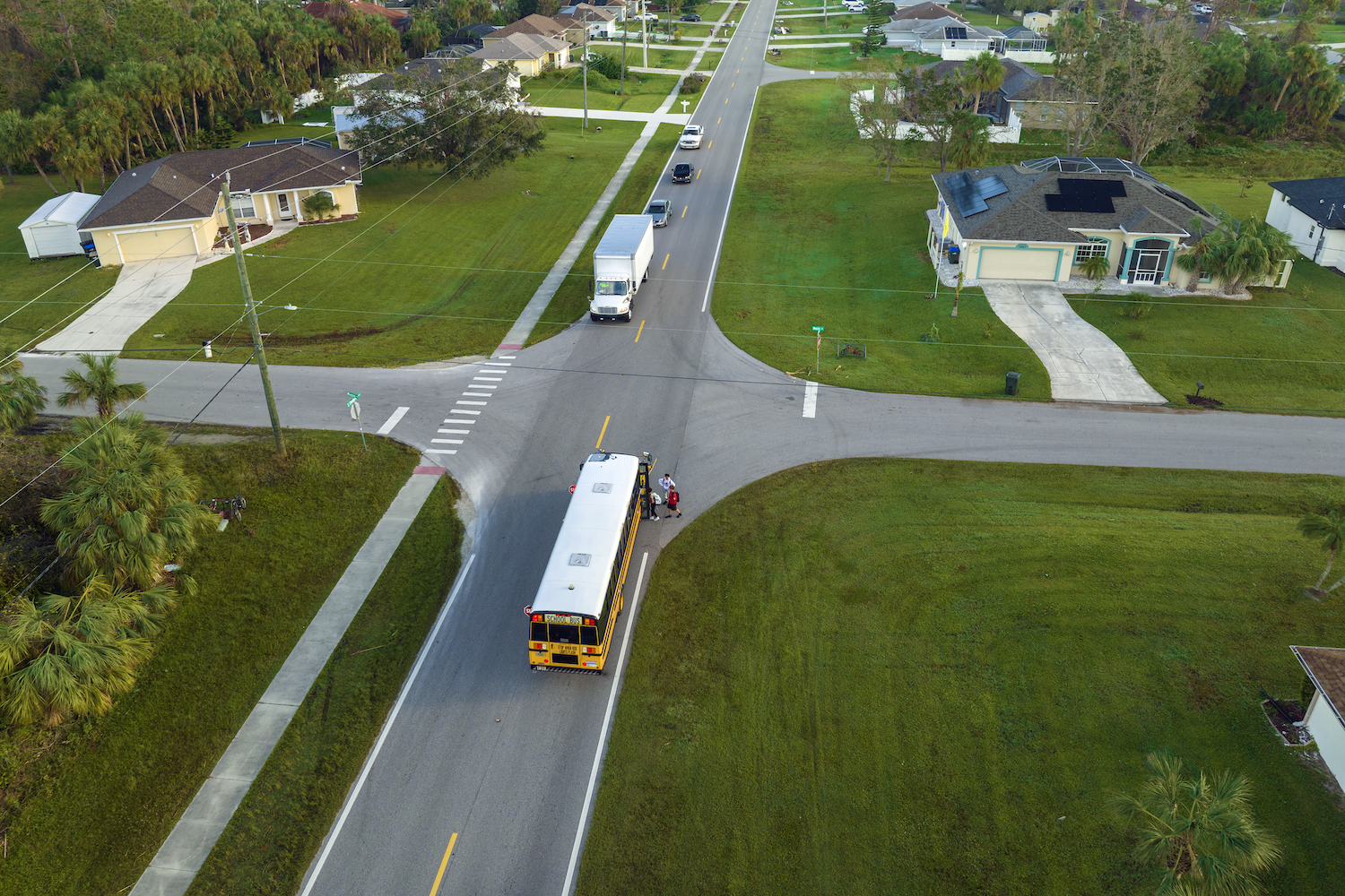An aerial shot of a neighborhood with a school bus, representing cyber volunteering in communities.