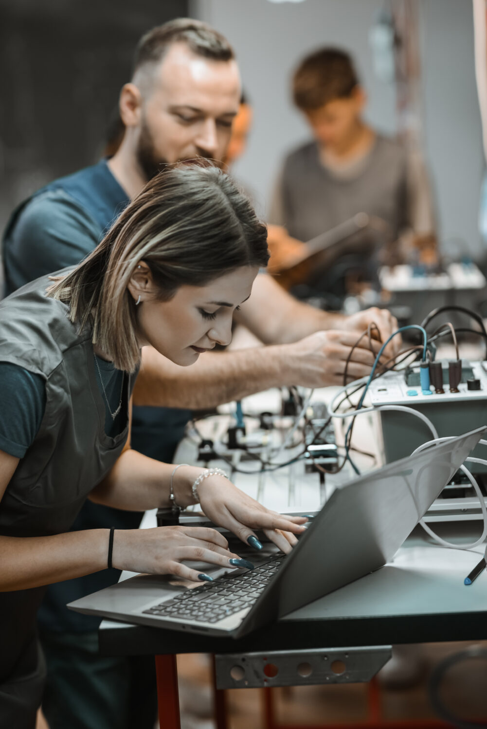 Photo of a female student learning how to code sequences into a PLC device through a laptop