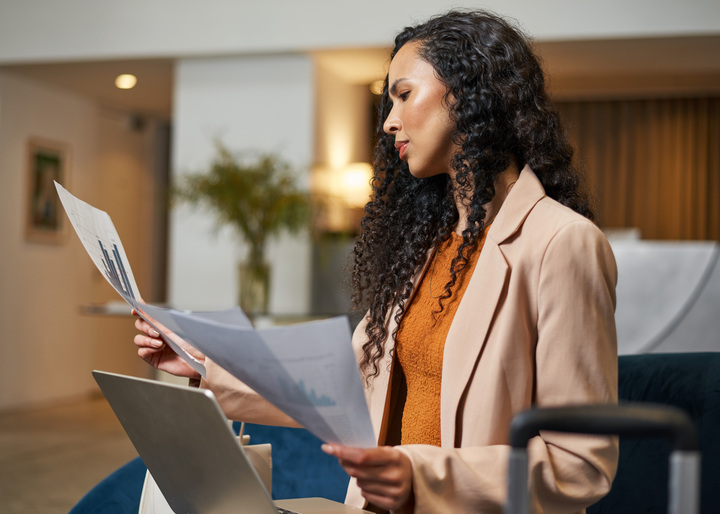 Woman in an office setting reviewing papers with graphs.