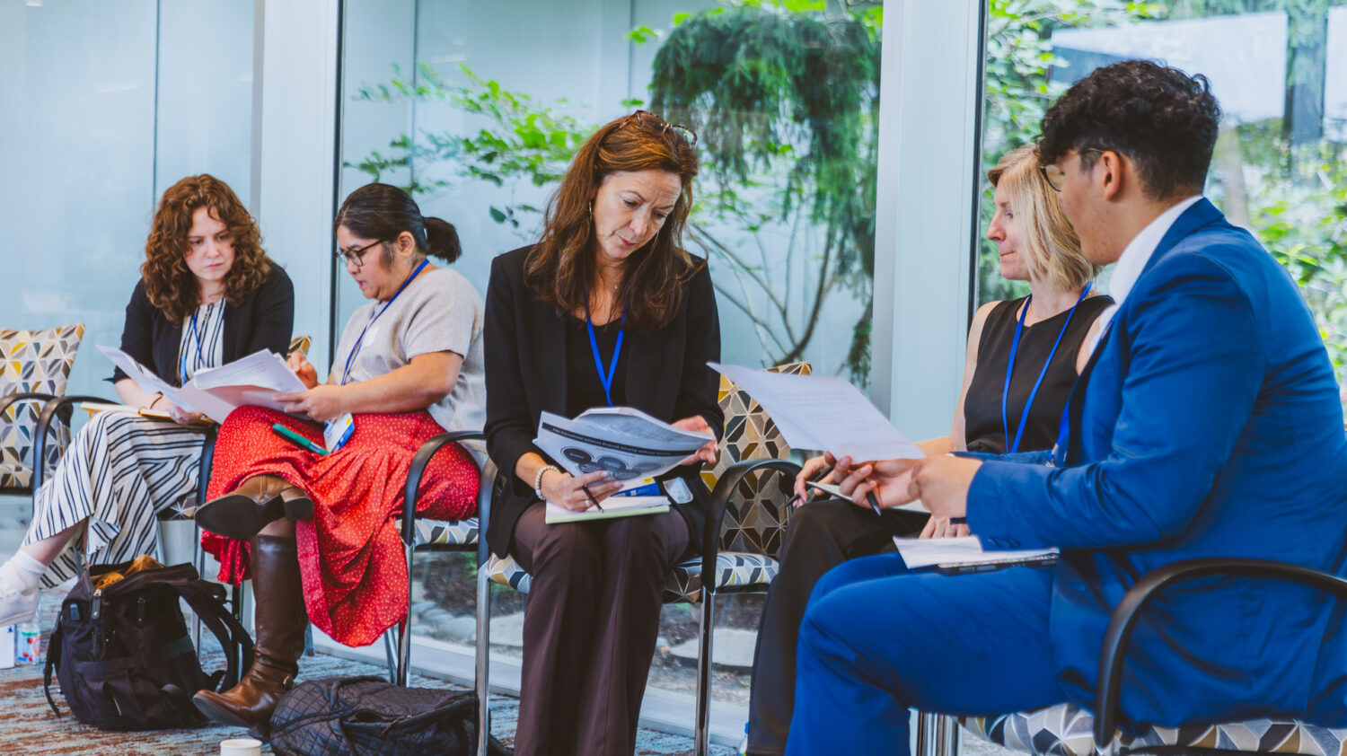 Five people review and discuss paper handouts.