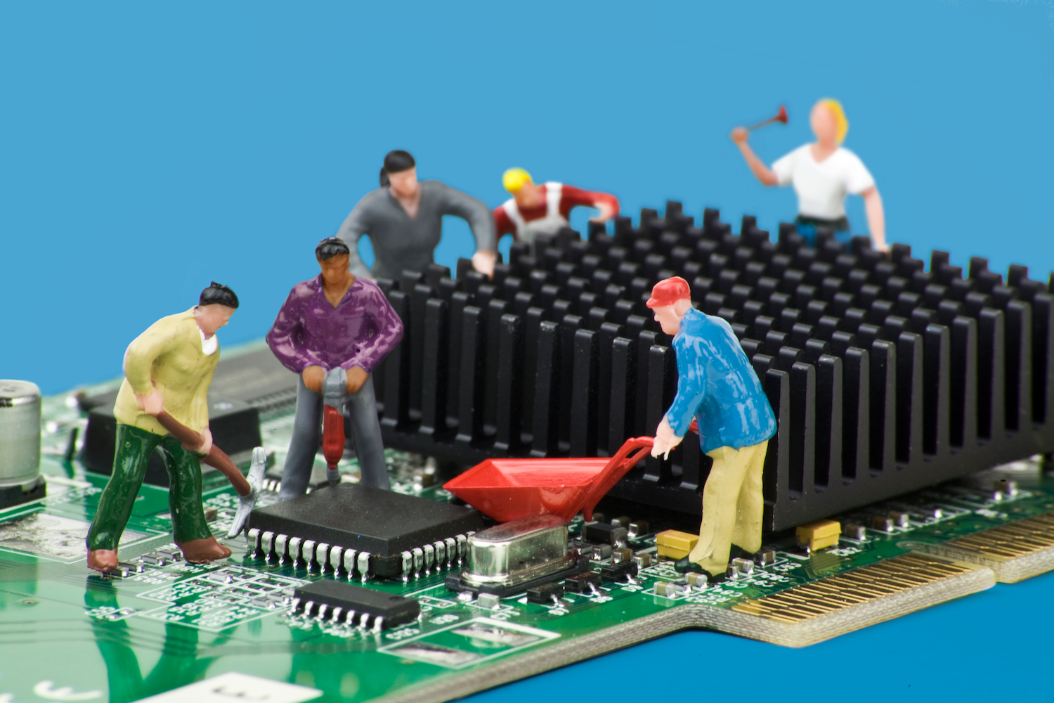 Miniature diorama of construction workers at work on a computer board (PCB).