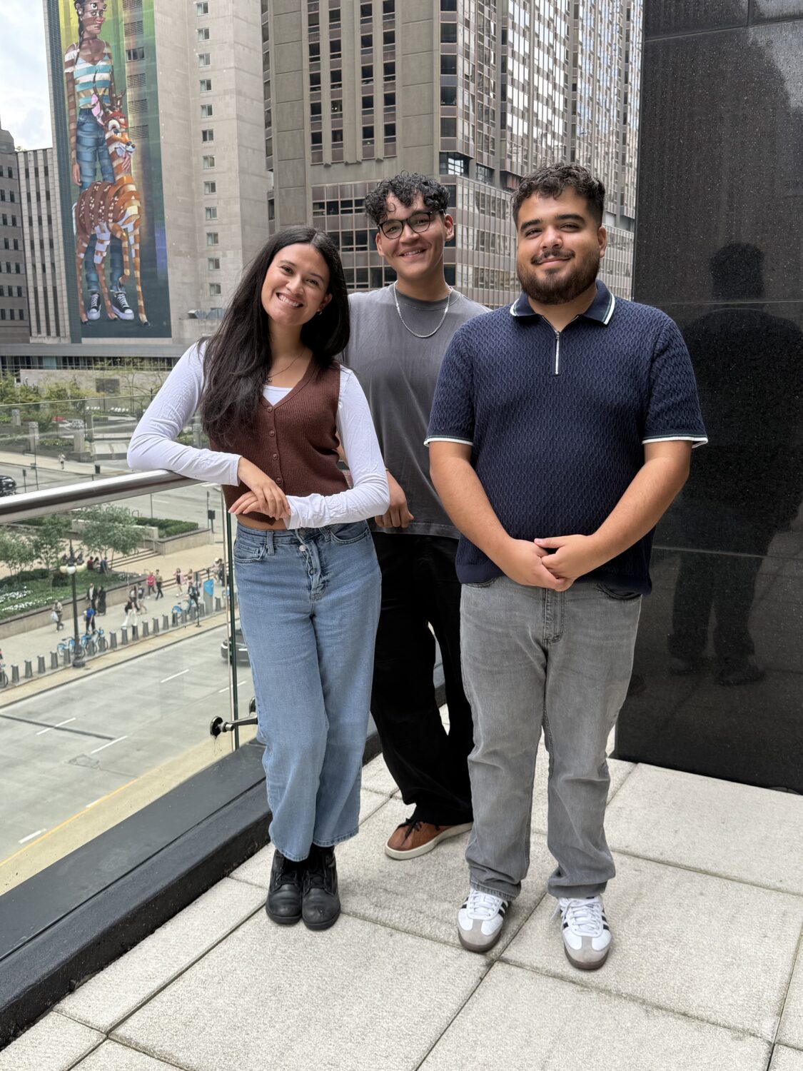 Three young adult CAG members pose on a balcony in Chicago.