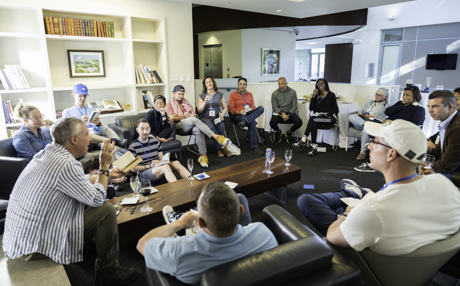 Seminar participants sit in a circle on sofas and chairs in a living room to engage in a group discussion.