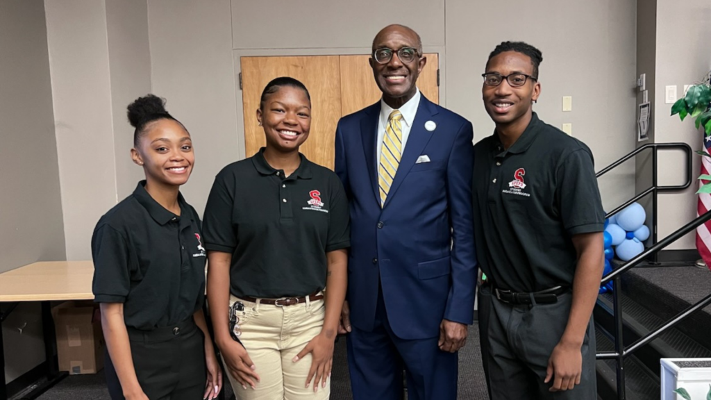 Three students pose for a photo with SFEPD founder, Ted Daniels. 