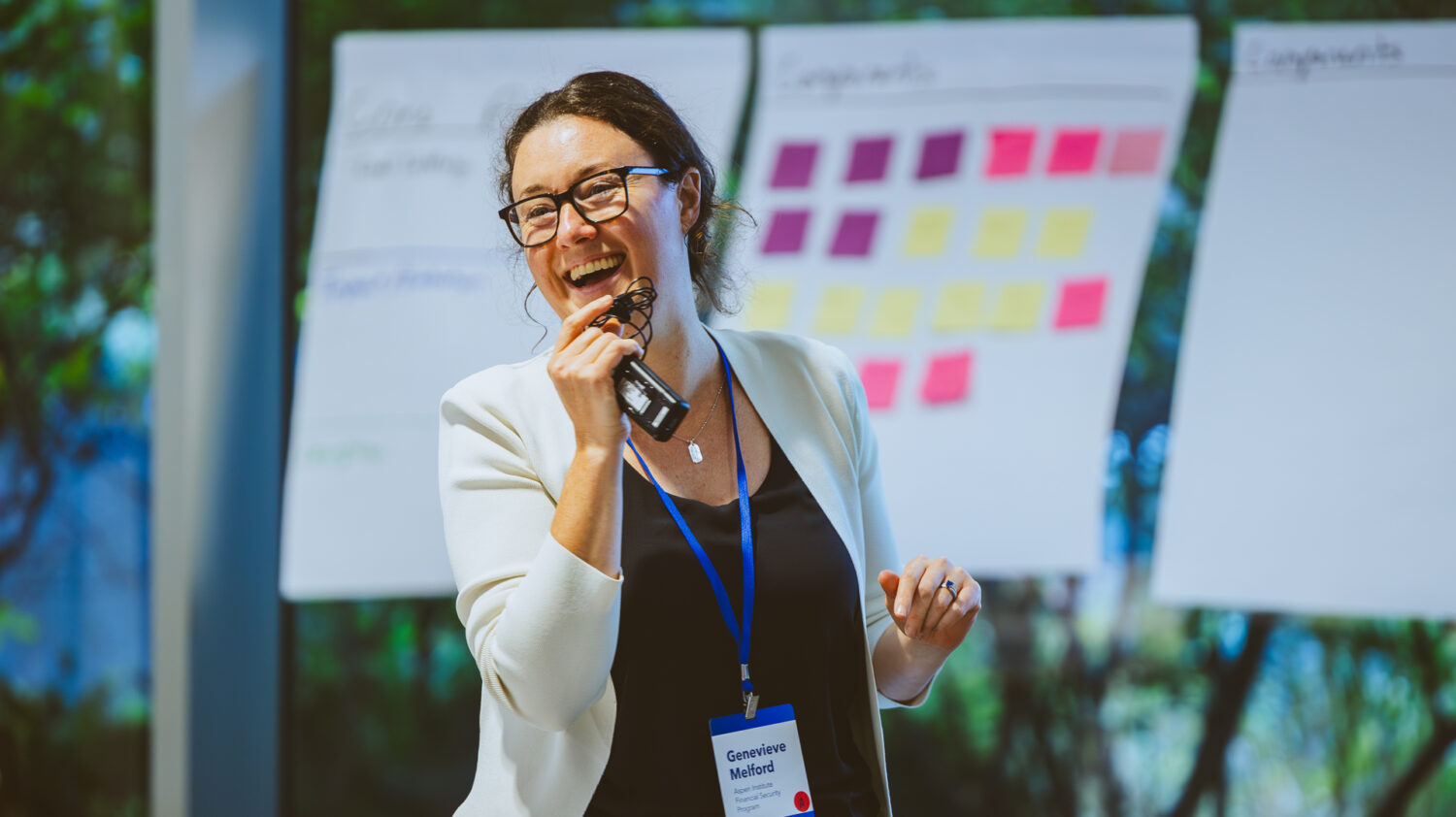 Genevieve Melford speaks at an event. Post it notes are seen in the background.
