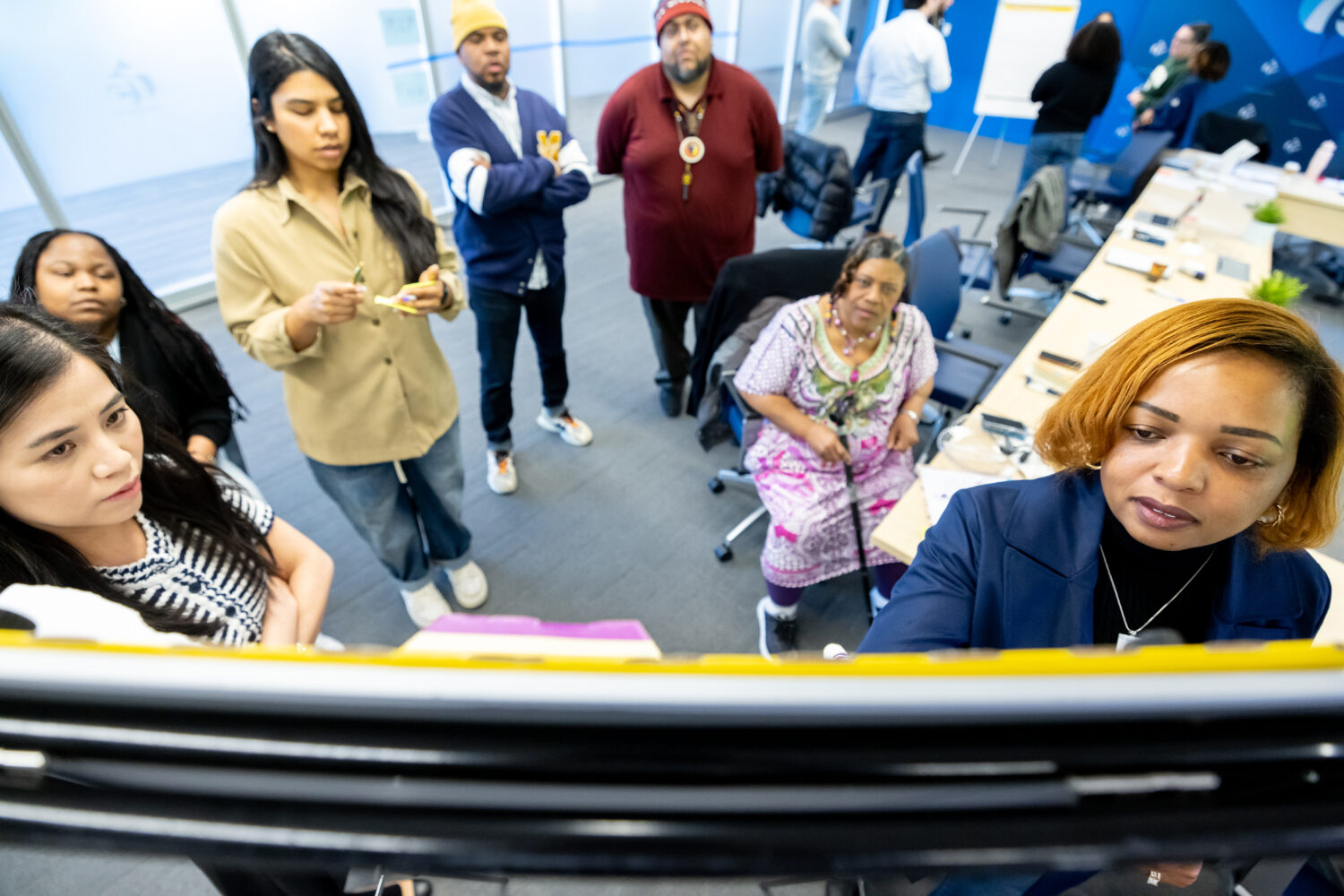 A photo taken from above shows a group of people writing on a flipchart.