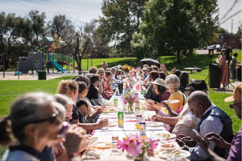 Neighbors enjoying a community meal and shaking hands. Photo credit: Andy Clayton-King