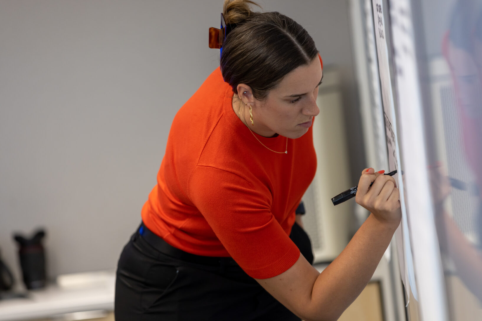 A woman writes on a board.